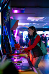 A young Latina woman smiling while playing arcade games in Akihabara, Tokyo, Japan, with glowing...