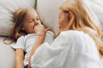 heartwarming moment woman and young girl sharing a tender touch on a cozy couch