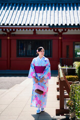 Young Latina woman in a colorful kimono, walking at Sensoji Temple in Asakusa, Tokyo, Japan, enjoying the cultural atmosphere.