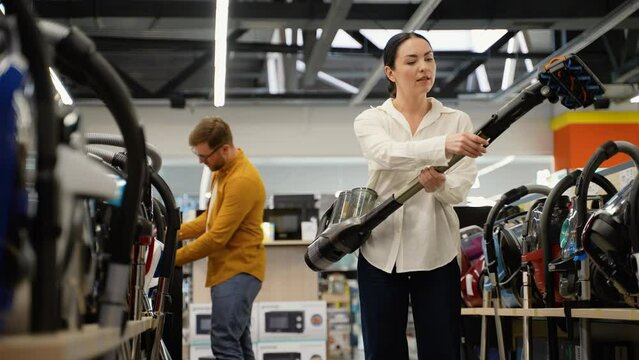 Young couple buying new vacuum cleaner at tech store for new home