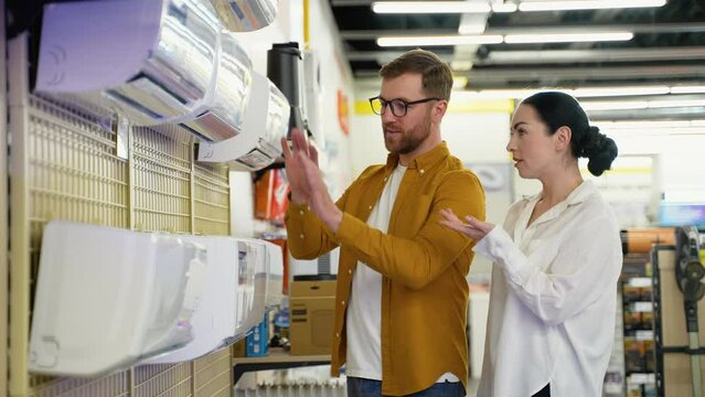 Just married young couple buying air conditioner in appliances store