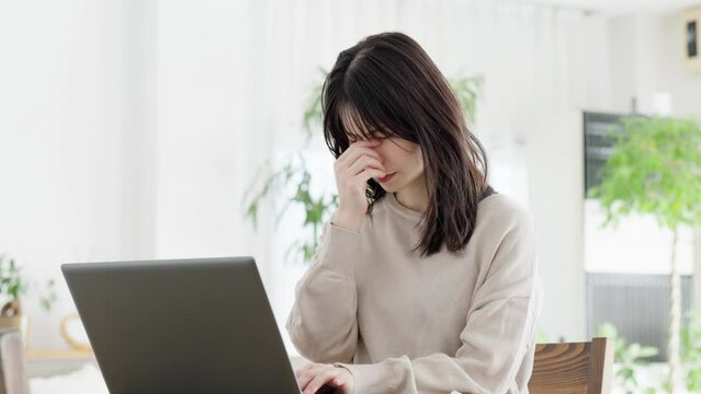 パソコン作業に目の疲れを感じる女性	
