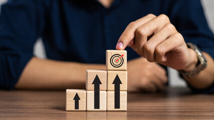 businessman hand pointing on dart board and arrow icon go up on wooden cube block stack, target...