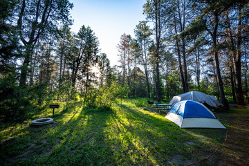 Tent camping amongst green grass with beautiful sun set.