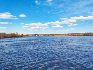 A natural landscape with a river and a blue sky. View of the Irtysh River