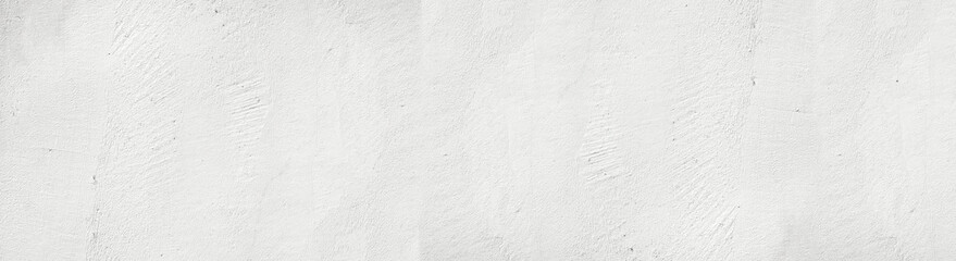 Large white grunge textured concrete wall background. The backdrop is a rough cement floor in gray and white tones.