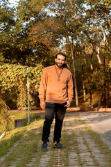 Latin man with long bearded hair and brown jacket, enjoying the golden hour in his country, trees and nature. Holidays and peace and quiet.