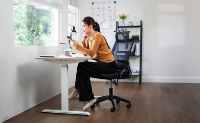 Young asian woman using mobile phone while sitting at desk  home office.