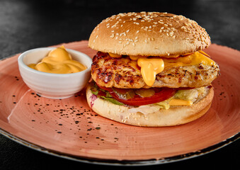 Delicious Chicken Fillet Burger with Cheesy Sauce on a Pink Plate