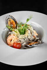 Gourmet Black Squid Ink Pasta With Seafood, Shrimps, Mussels, and Cherry Tomatoes on White Plate