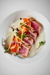 Gourmet Tuna Tataki with Fresh Vegetables and Cream Sauce on White Plate