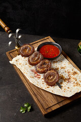 Beef Skewers with Lamb Fat Rolls on Flatbread and Tomato Sauce