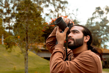 Long-haired, bearded Latino man in a brown jacket documenting his holiday and enjoying the golden hour in his country. World photography and travel day.
