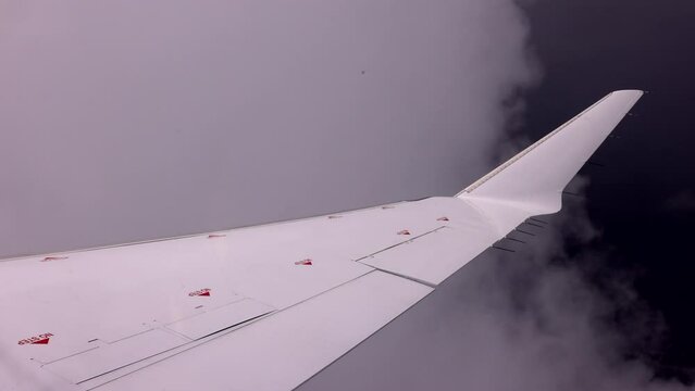 Airliner - pov scene of white wing passing through cloud cover - right after take off - close uf of winglet fin at the end of the airliner wing