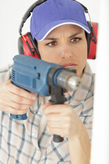 serious woman drilling wall in new house