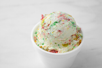 A view of one small scoop of birthday cake ice cream in a styrofoam cup.