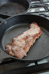 A view of a New York steak in a large cast iron skillet.