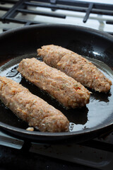 A view of some chicken sausages cooking in a fry pan.