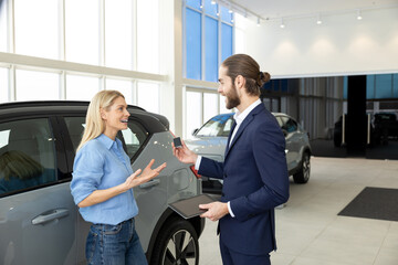 Blonde female customer talking to a sale assistant in a car salon