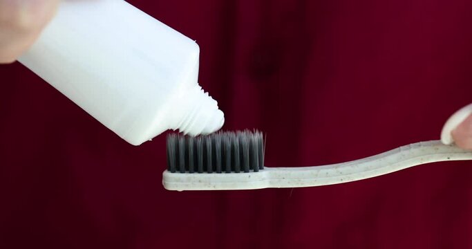 Female hand squeezes fresh toothpaste onto toothbrush