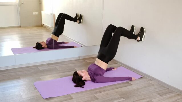 Athletic 30 year woman is doing bridge exercise raising pelvic lying on rubber mat. Sporty girl pumps up the abs and legs. Warming muscles. Healthy lifestyle concept. To build the strong body. 4K