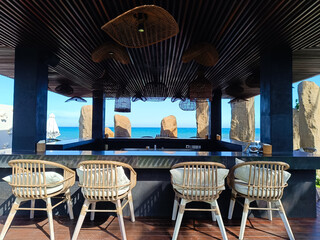 serene and stylish rooftop bar with a stunning ocean view, featuring modern rattan chairs and unique lighting fixtures, perfect for a relaxing getaway