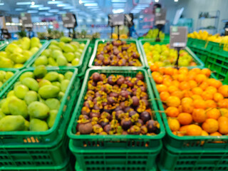 blurred, wide-angle view of a brightly lit supermarket produce section, with several green plastic crates filled with various fresh fruits, creating a vibrant display of healthy food