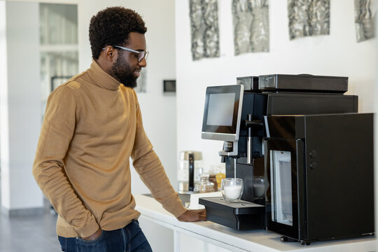 Man office worker using modern coffee machine making coffee in office