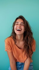 Young woman laughs brightly with a teal wall in the background