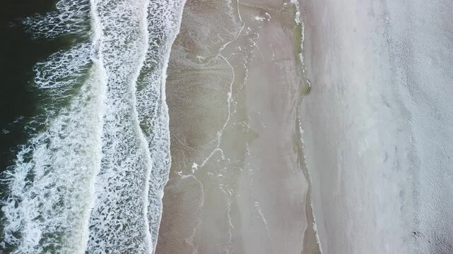 Beach drone shot above the water with waves breaking on the shore