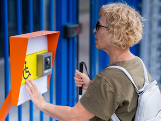 An elderly blind woman reading a text in braille. Button for calling help for people with disabilities. 