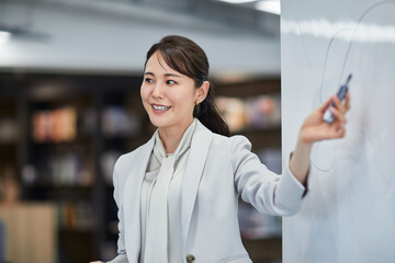 ホワイトボードを使い会議をするビジネスウーマン
