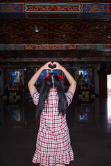 A young woman raises her hands to make a heart symbol meaning love and friendship. Concept of ​​using hands to make a heart symbol represents the meaning of friendship, love and kindness. Copy Space