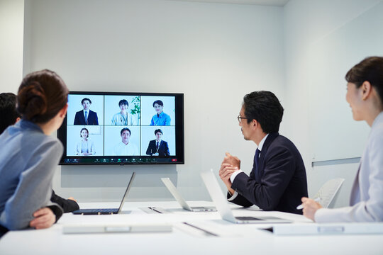 オフィスでオンライン会議をするビジネスマンとビジネスウーマン