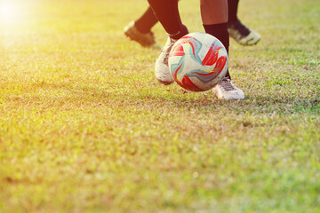 Indonesian boy's feet are dribbling the ball while playing football on the soccer field