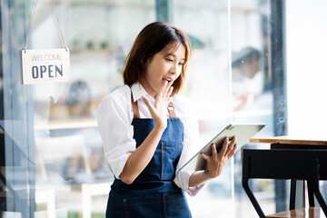 Small business owner sme beauty girl stand with tablet smartphone in coffee shop restaurant. Portrait of asian tan woman barista cafe owner. SME entrepreneur seller business conce