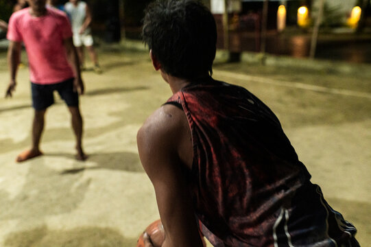 Filipino friends playing basketball on outdoor court at night, Philippines, Asia