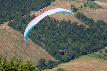 Sestola, Italy - 07 27 2024: Paraglider flies in the air. Aerial view of paragliding. Paraglider...