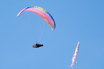Serramazzoni, Italy - 06 19 2024: Paraglider flies in the air. Aerial view of paragliding. Paraglider flies in a bright sunny day. Concept of extreme sport.
