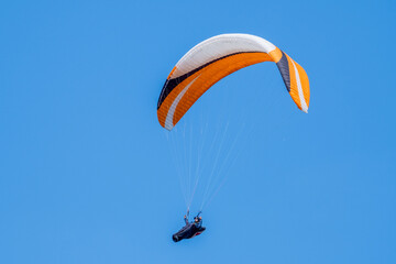 Serramazzoni, Italy - 06 19 2024: Paraglider flies in the air. Aerial view of paragliding. Paraglider flies in a bright sunny day. Concept of extreme sport.
