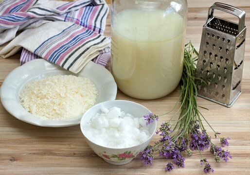 Homemade laundry detergent made from grated soap, crystalline sodium, essential oil and water. Lavender herb and crystalline sodium in front, ready detergent in the bottle at back.