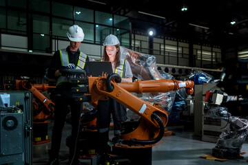 Fototapeta premium team engineers inspecting on machine with smart tablet. Worker works at heavy machine robot arm. The welding machine with a remote system in an industrial factory. Artificial intelligence concept.