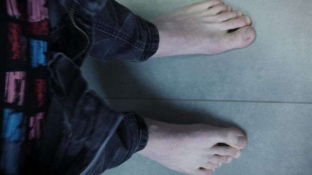 Male in jeans and underwear with bare feet sitting on toilet. Vertical video