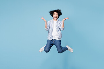 Obraz premium Full body shocked surprised young man he wears shirt white t-shirt casual clothes jump high spread hands looking camera isolated on plain pastel light blue cyan background studio. Lifestyle concept.