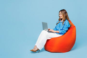 Full body young smart IT woman she wear shirt casual clothes sit in bag chair hold use work on...