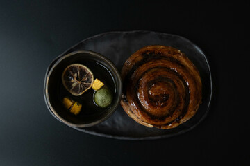Coffee Break , Teat-Time , Dessert Concept, Cinnamon Roll with Herbal Tea on Black background