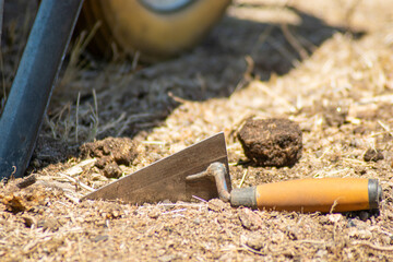 selective focus, a trowel on the ground with a wheelbarrow in the background in an archaeological excavation