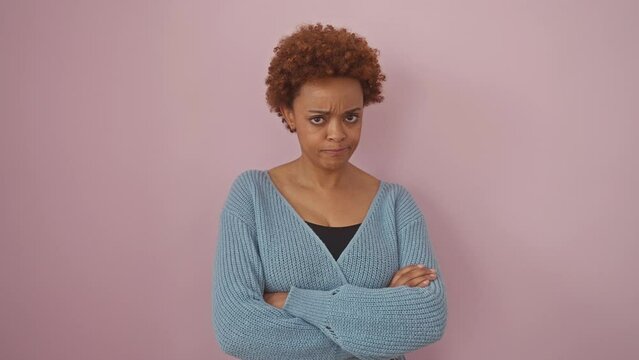 African american woman wearing sweater standing skeptic and nervous, disapproving expression on face with crossed arms. negative person. over isolated pink background