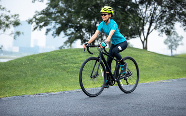 Obraz premium Woman biking in summer city park