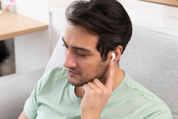 Fototapeta premium Close-up photo of young man in wireless earphones listening to music